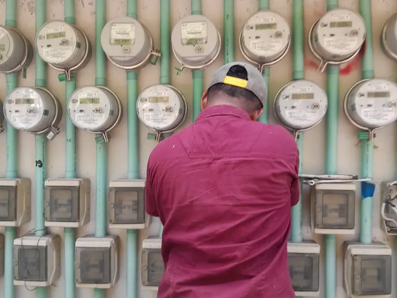 Electricista revisando un banco de medidores de CFE en un edificio de Cancún